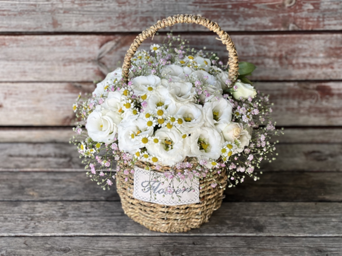 A white arrangement with pink gypsophila in a basket
